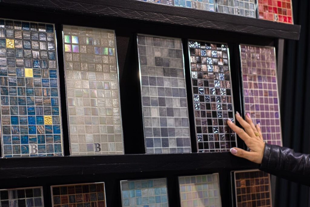 Campioni di mosaico colorati su scaffale; mano che li tocca.